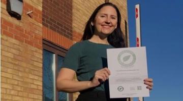 Picture shows climate change officer Emma Danielsson holding the silver certificate. Behind her are swift boxes installed at The Grange to help support nature.