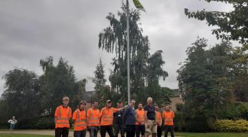 Parks and open team in front of the green flag